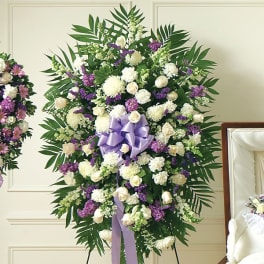 Standing floral spray with white and purple flowers and a lavender ribbon