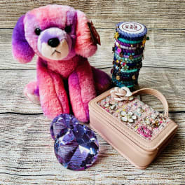 Pink and purple plush dog with a beaded bracelet stack and jeweled case