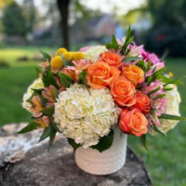 Bouquet of orange roses and white hydrangeas in a white vase