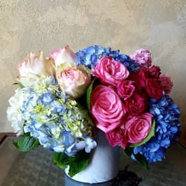 Bouquet of pink roses and blue hydrangeas in a white vase