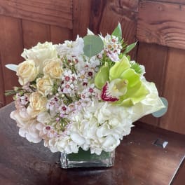 White and pale pink floral arrangement in a square glass vase