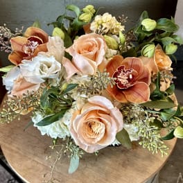 Peach roses and orange orchids in a low bouquet