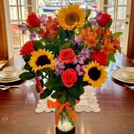 Bouquet of sunflowers, roses, and alstroemeria in a glass vase