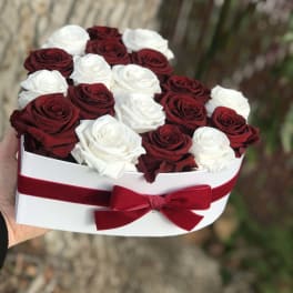 Heart-shaped box of red and white roses with a red ribbon bow