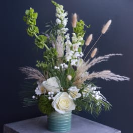 White roses and snapdragons in a teal vase with airy grasses