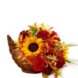 Autumn flower arrangement in a woven cornucopia basket with sunflowers and roses