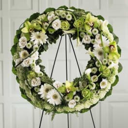 Circular floral wreath on a stand with white and green flowers