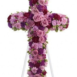 Cross-shaped floral tribute with pink and purple roses and mums on an easel