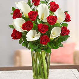 Red roses and white calla lilies in a clear glass vase