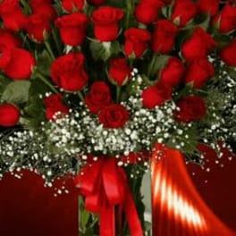 Bouquet of red roses in a clear glass vase with a red ribbon