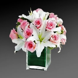 Pink roses and white lilies arranged in a clear square vase