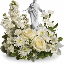 White floral arrangement with a small religious statue in the center