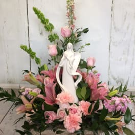Pink floral arrangement with a white angel figurine centerpiece