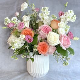 Pink, peach, and white flowers arranged in a white vase