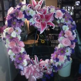 Heart-shaped floral wreath with pink lilies, roses, and purple daisies