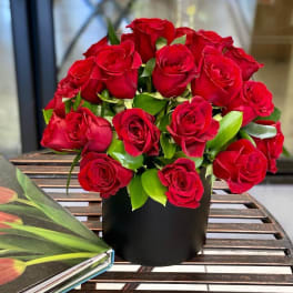 Red roses arranged in a black round box