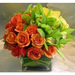 Orange roses and yellow orchids in a square glass vase