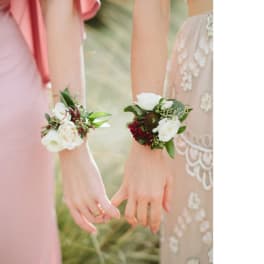 Two women wearing floral wrist corsages at a wedding