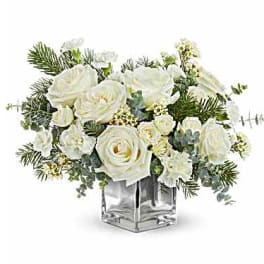 White roses and small white flowers in a clear square vase