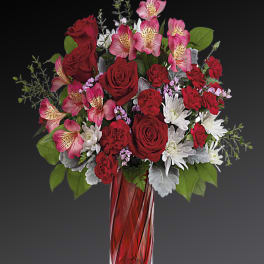 Red roses and pink alstroemeria in a red glass vase