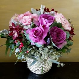 Pink and purple floral arrangement in a white patterned vase