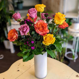 Mixed roses in pink, orange, and yellow in a white vase