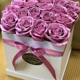 Pink roses arranged in a white square box with a ribbon bow