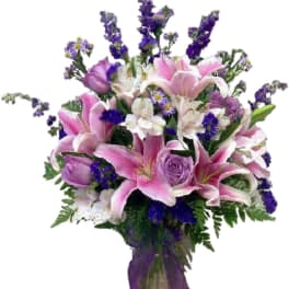 Bouquet of pink lilies, purple roses, and white flowers in a vase