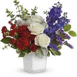 Red carnations, white roses, and purple flowers in a clear square vase