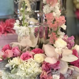 Pink and white floral arrangement with a clear cross centerpiece