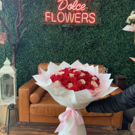 Large bouquet of red and white roses wrapped in white paper with a pink ribbon
