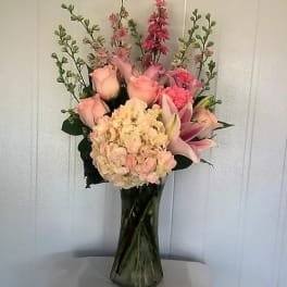 Pink and peach floral arrangement in a tall glass vase