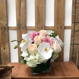 Pink and white floral arrangement in a square glass vase
