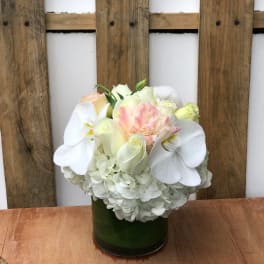 White hydrangea and pale roses in a green glass vase