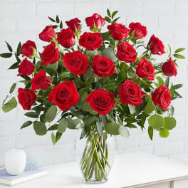 Tall arrangement of long-stemmed red roses in a clear glass vase