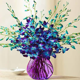 Blue and purple floral arrangement in a purple glass vase