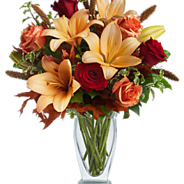Bouquet of orange lilies and red roses in a clear glass vase