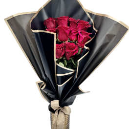Bouquet of red roses wrapped in black paper with a beige ribbon bow