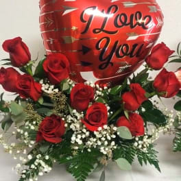 Red roses arranged around a heart balloon that says I Love You.