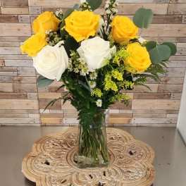 Yellow and white roses in a clear glass vase