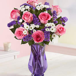 Pink roses and white-purple filler flowers in a purple glass vase