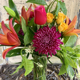 Bouquet of roses, lilies, and a chrysanthemum in a glass vase