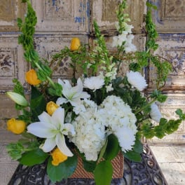 White lilies and yellow roses arranged in a wicker basket