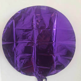 Purple round foil balloon against a white wall