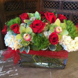 Red roses and white hydrangeas in a glass vase with a red ribbon