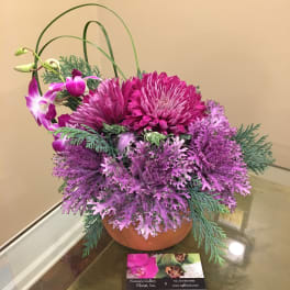 Purple floral arrangement in a terracotta bowl with arching orchid stems
