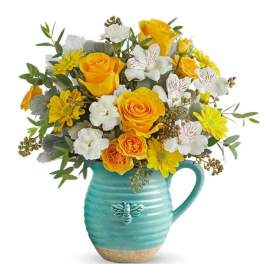 Yellow and white flower bouquet in a turquoise pitcher vase