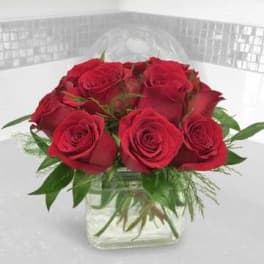 Red roses arranged in a clear square glass vase
