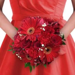 Bridal bouquet of red roses and gerbera daisies held against a red dress