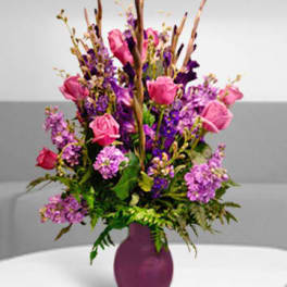 Pink and purple flower arrangement in a purple vase